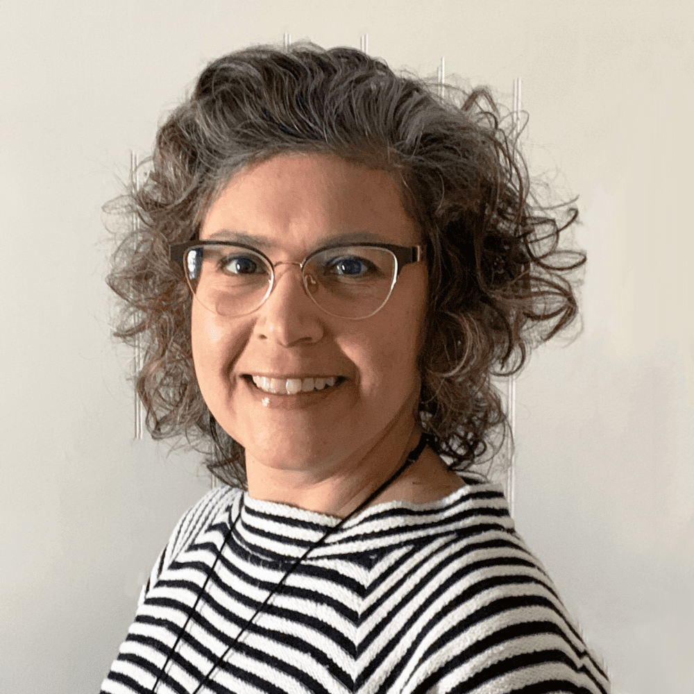 A woman with curly hair wearing glasses and striped shirt.