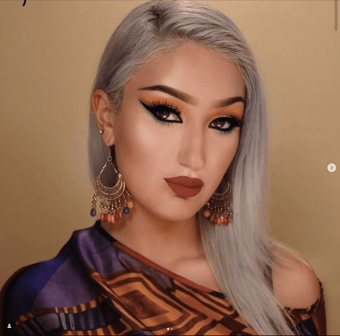 A woman with long silver hair and bright makeup.